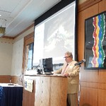 A man stands behind a podium reading from a computer screen